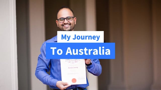 A smiling man holds his Australian citizenship certificate